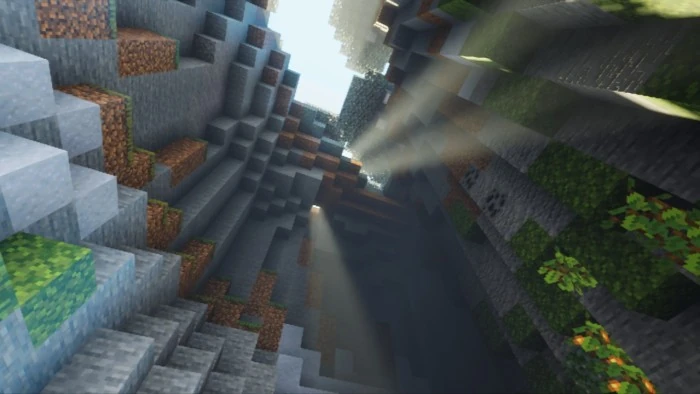A cave opening lets bright light reach into the darker rock interior.