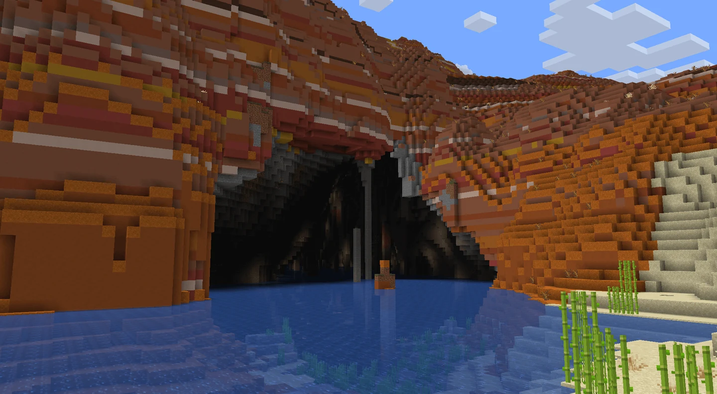 A river enters a large cave beneath layered badlands terrain
